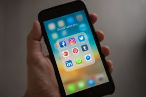 A cell phone with social media icons representing a parent held in contempt for posting negative comments about former partner online